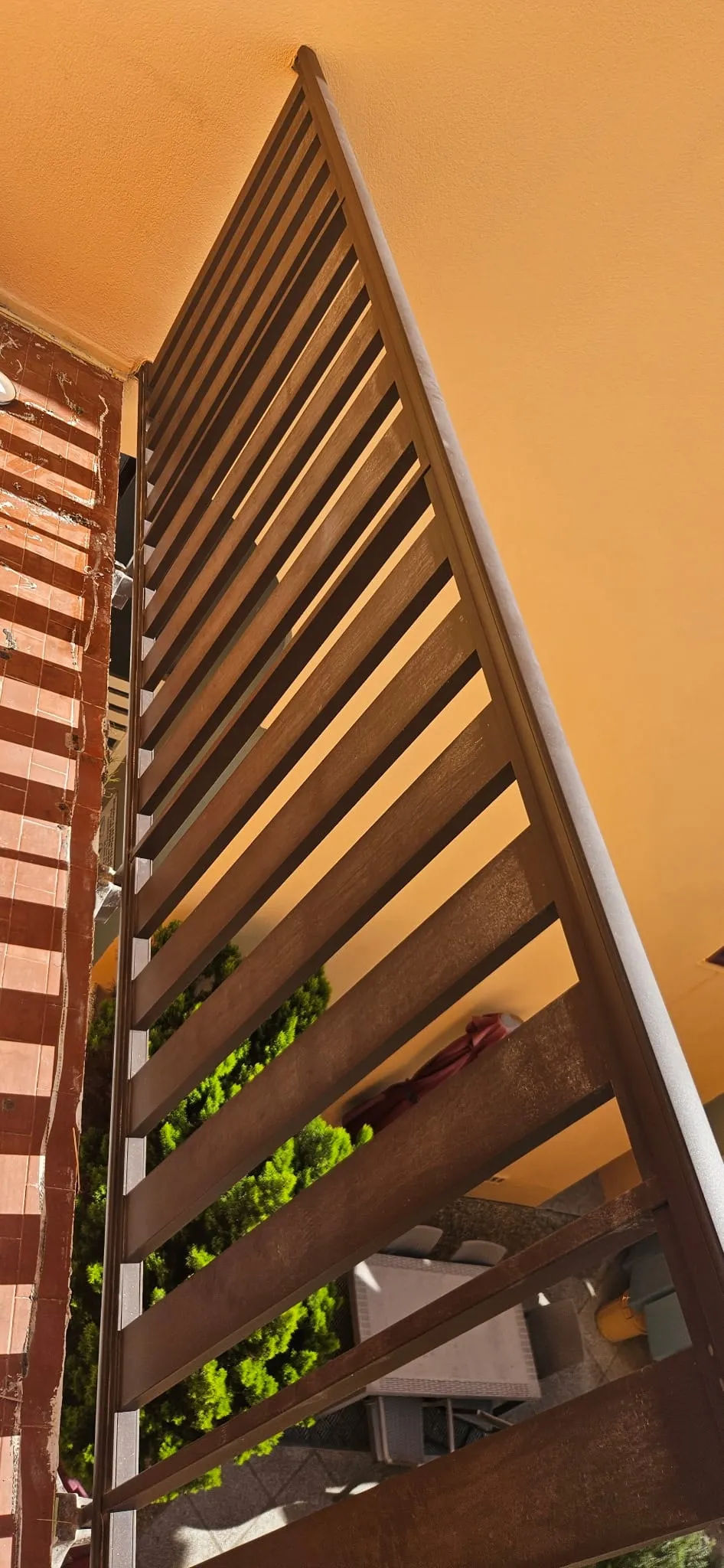 Balcon avant la pose : garde-corps à lames ajourées, vue dégagée sur la cour en contrebas