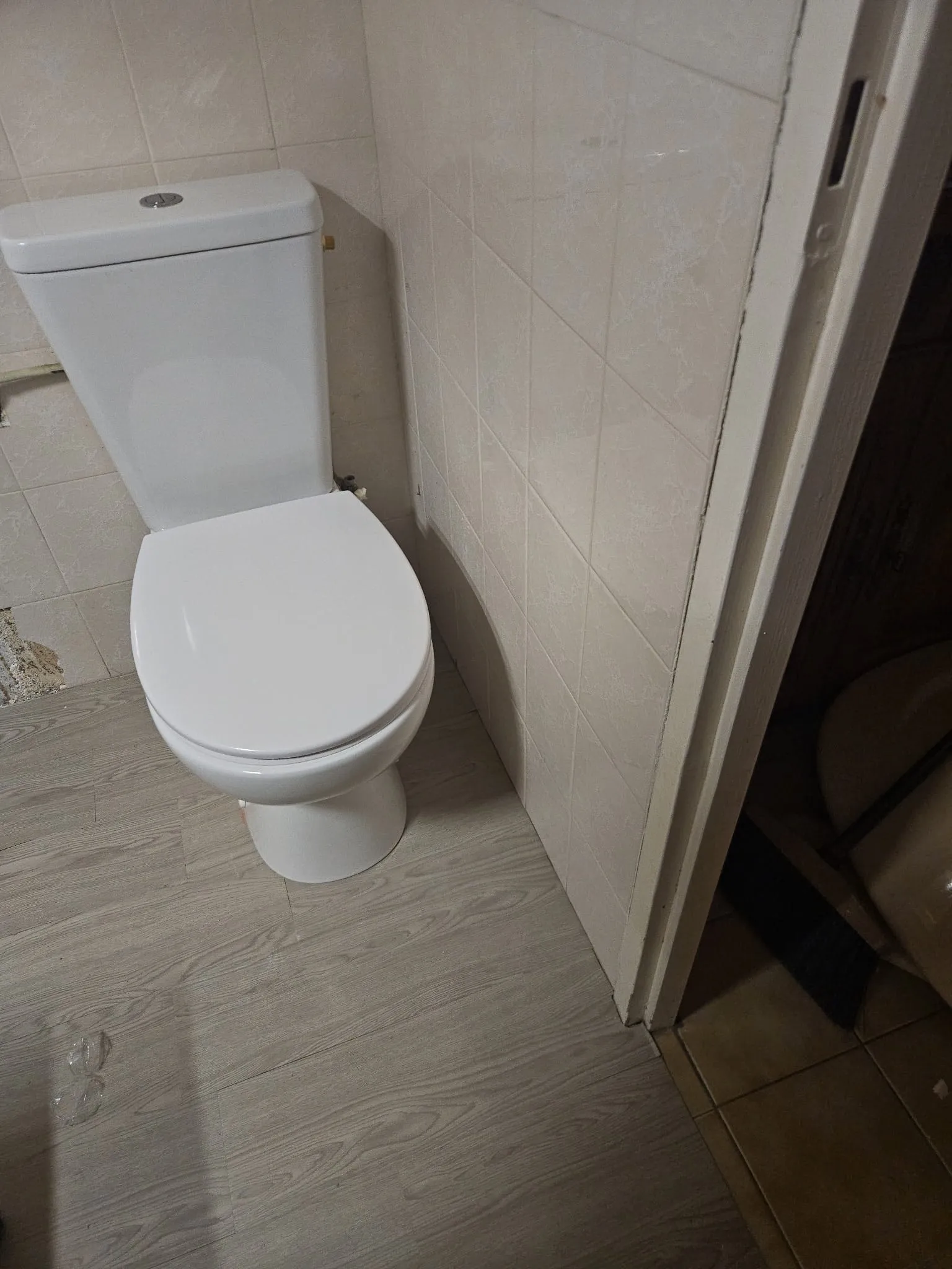 Salle d’eau après travaux : WC neuf blanc posé sur un sol en lames effet bois gris clair