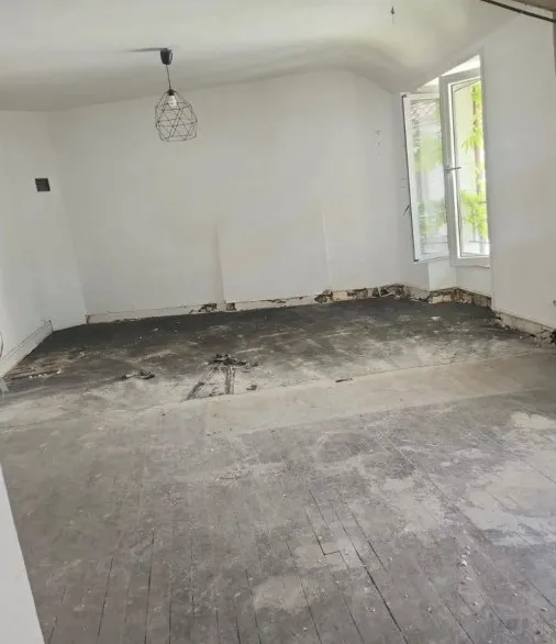 Séjour avant travaux : ancien plancher déposé, chape et lambourdes apparentes, murs nus